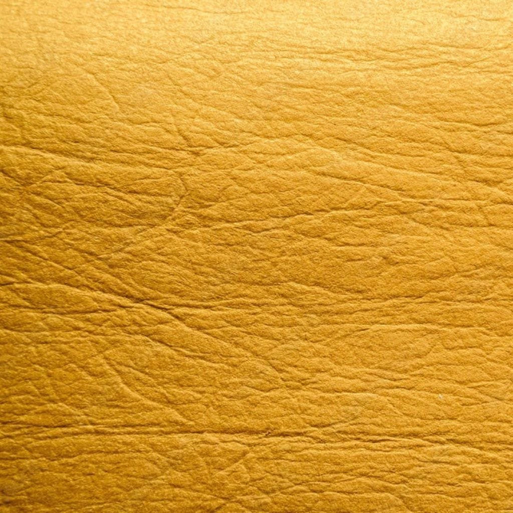 Vegan Leather – Ethical, Sustainable, and Durable Leather Alternative. Close-up texture of vegan leather with a smooth and uniform surface in a golden-yellow hue.