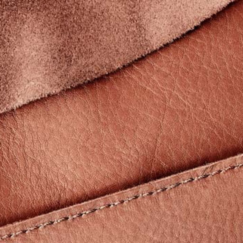 Close-up of vegetable-tanned leather showcasing its natural texture, earthy tone, and fine stitching.