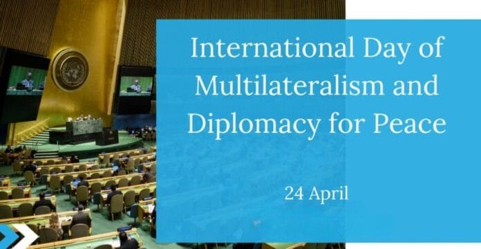 A view of the United Nations General Assembly hall with a large screen displaying speakers. The text 