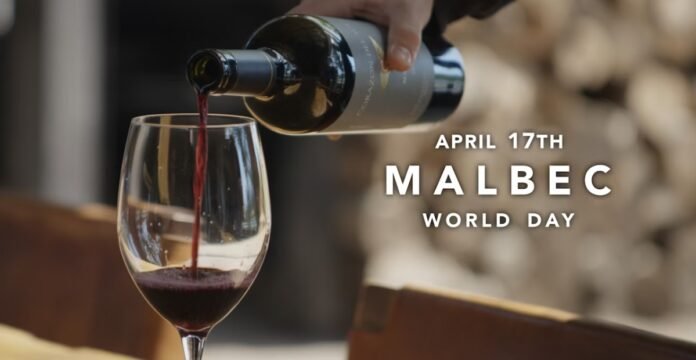 A hand pouring a red wine from a bottle into a glass on a wooden table, accompanied by the text 