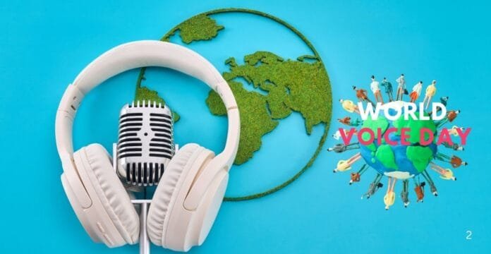 A graphic representation for World Voice Day featuring a globe made of green grass, a vintage-style microphone, and white headphones against a vibrant blue background. The text 