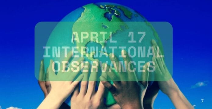 A diverse group of hands of various skin tones is holding a globe, symbolizing unity and global cooperation. The background features a bright blue sky.