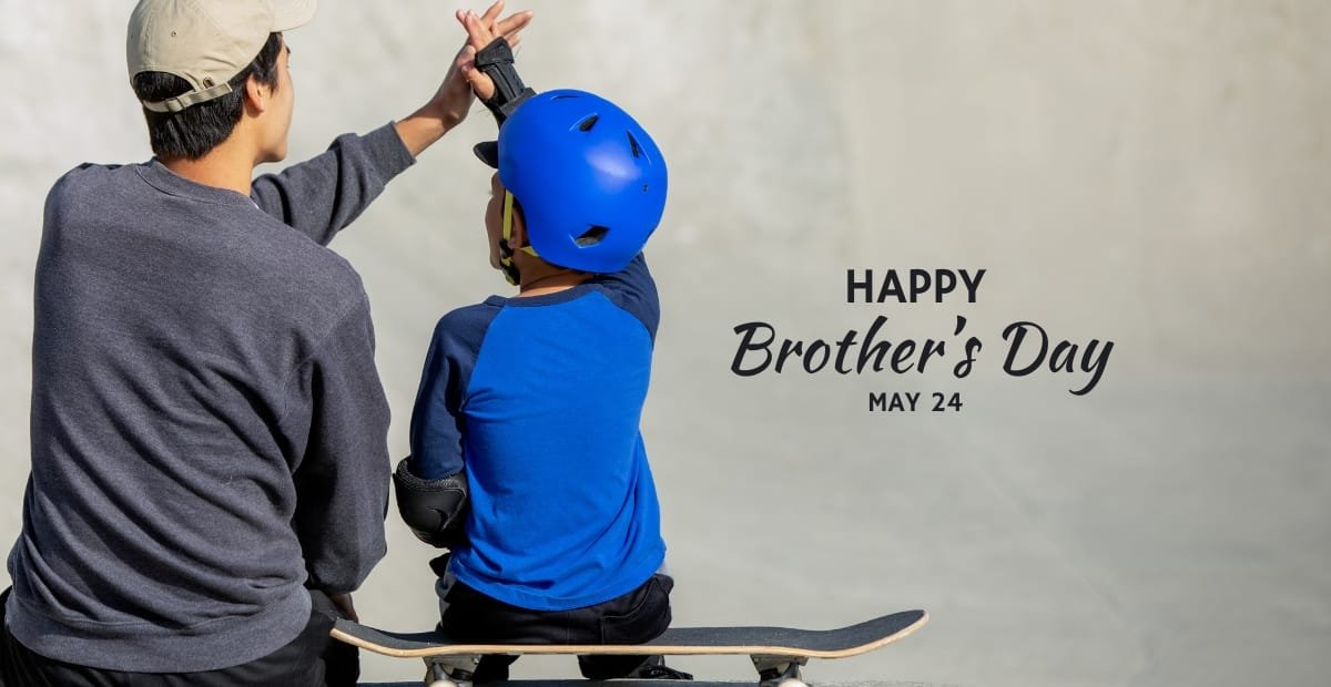 Brother’s Day – Celebrating the Bond of Brotherhood on May 24 A young boy wearing a blue helmet sitting on a skateboard with an adult giving him a high-five, celebrating brotherhood.