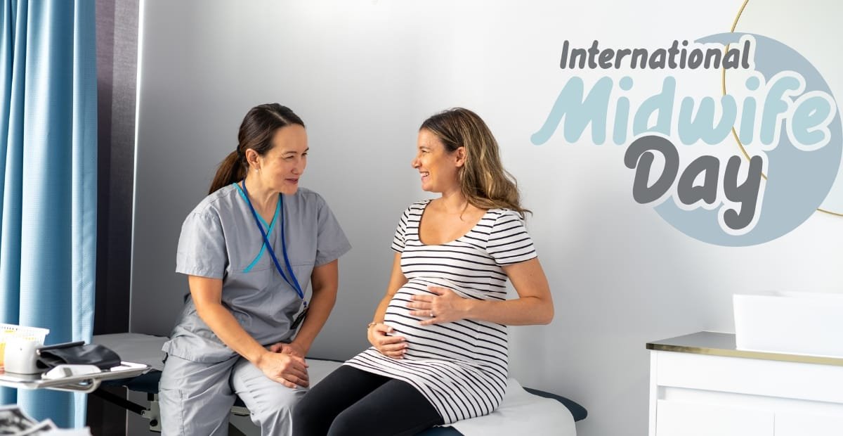 A pregnant woman sitting on a hospital bed, smiling and gently touching her belly while talking to a medical professional. The background features a sign that reads "International Midwife Day."