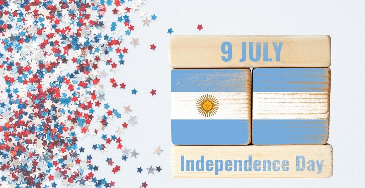 A celebration of Argentina's Independence Day featuring wooden blocks with the Argentine flag, the date "9 July," and "Independence Day" written on wooden signs, accompanied by scattered red, white, blue, and silver star-shaped confetti on a white background.