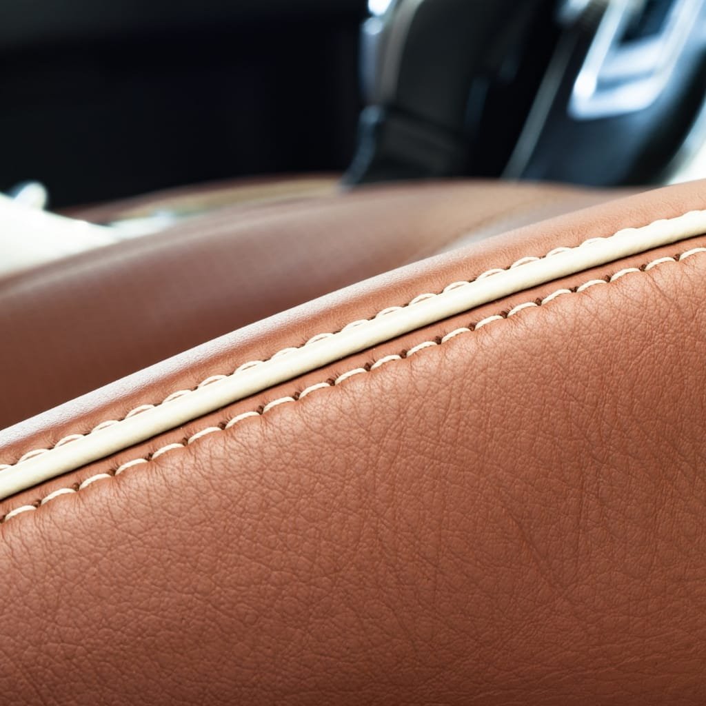 Cow’s Leather: Durable, Timeless, and Perfect for Every Style 17 Close-up shot of a tan leather car seat with white contrast stitching, showing the textured surface and stitching detail.