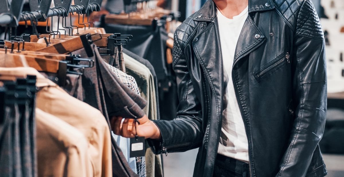A person wearing a black buffalo leather jacket while shopping for clothes in a store.