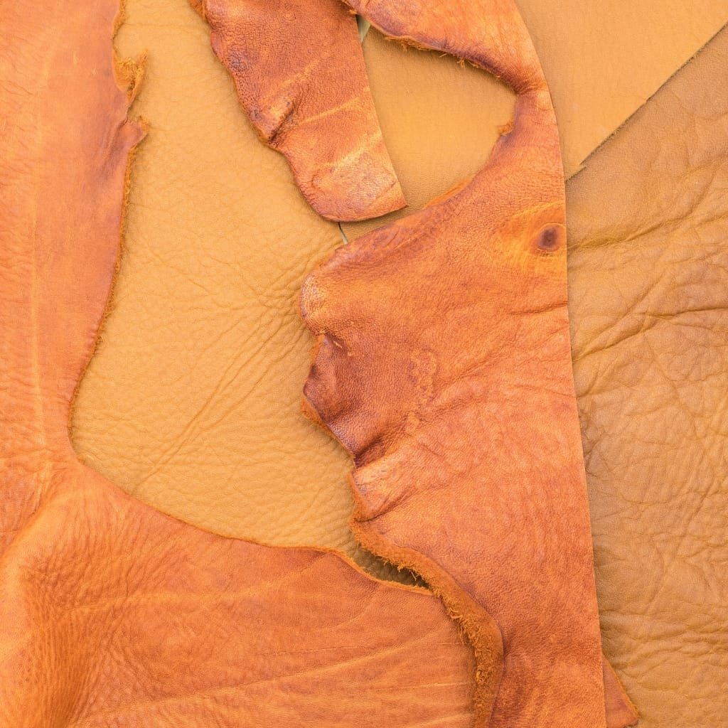 Close-up image of torn and layered buffalo split leather showing its textured surface and varying shades of tan and brown