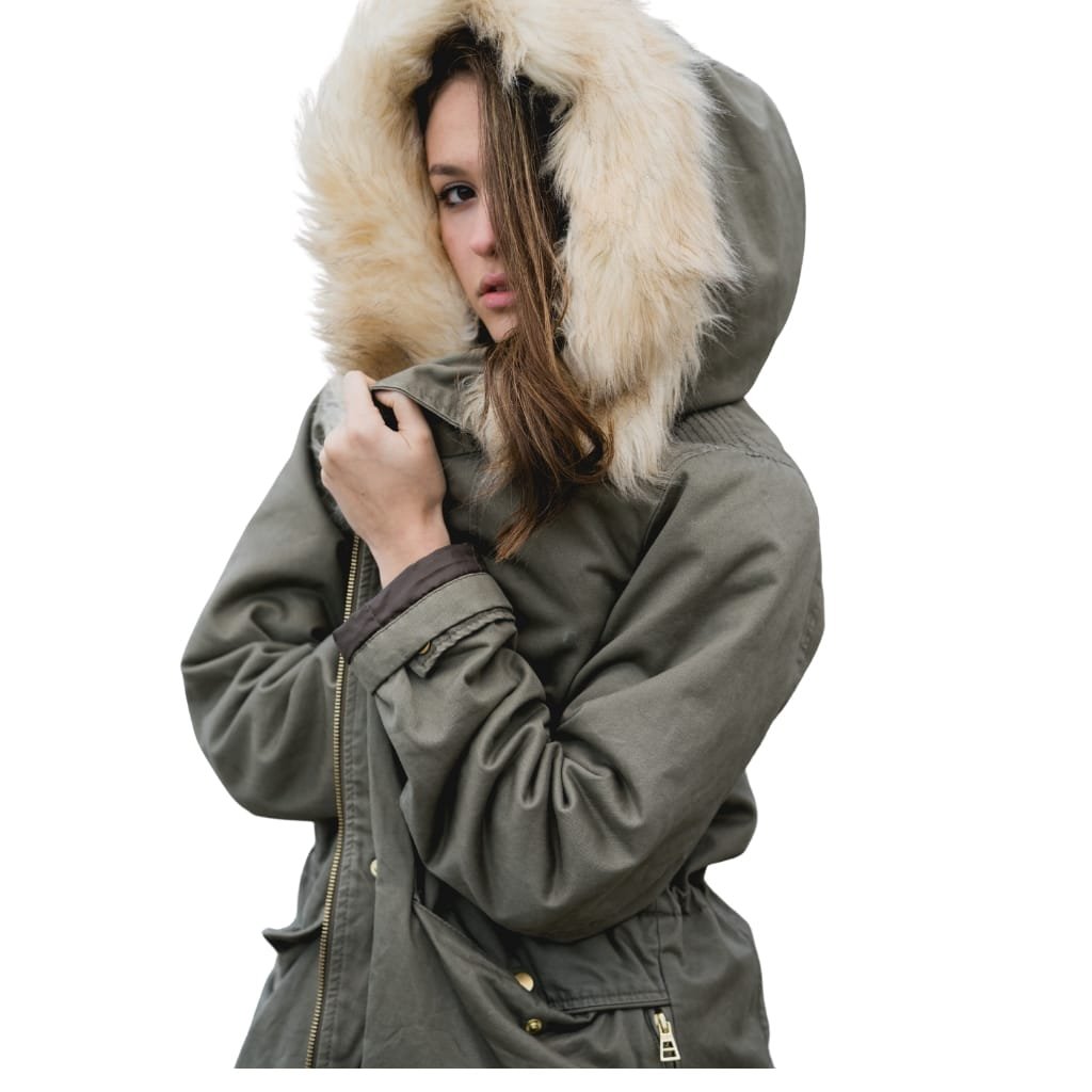 A woman wearing a stylish, oversized military green jacket with a large, fluffy fur-lined hood. She has long, wavy brown hair partially covering her face, and she is holding the collar of her jacket with one hand against a plain white background.