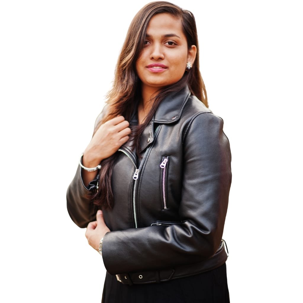 A young woman with long, wavy brown hair, wearing a black leather jacket, earrings, and a bracelet, standing against a white background.
