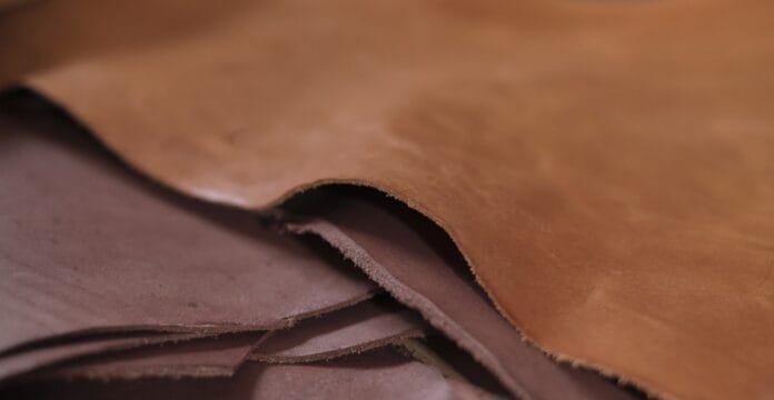 Close-up image of stacked pieces of full grain leather with a natural, smooth surface and visible texture.