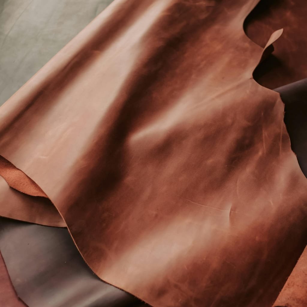 Close-up of a piece of full grain leather with rich, natural variations in color and texture, showcasing its high-quality finish.

