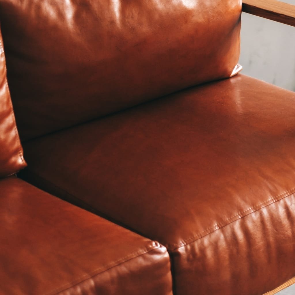 Cow’s Leather: Durable, Timeless, and Perfect for Every Style 16 Close-up of a brown leather sofa with visible stitching and a soft sheen, showing the cushion and part of the armrest.