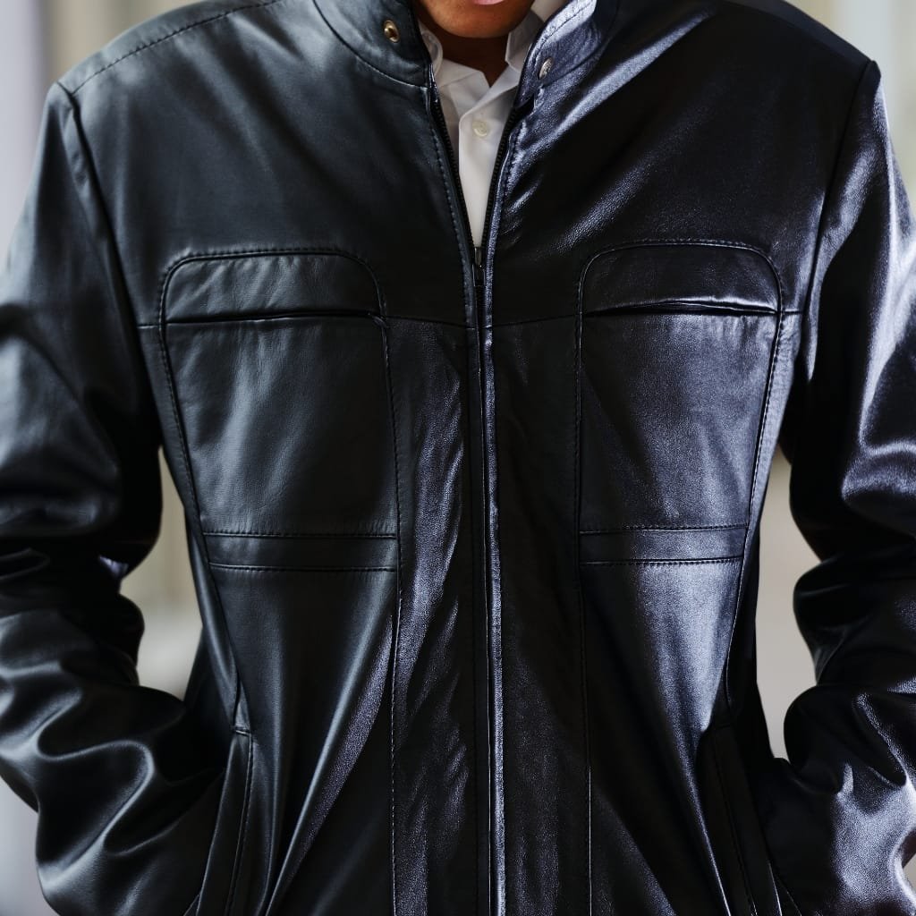 What Is a Leather Jacket? A Timeless Icon of Style and Attitude 38 Close-up of a person wearing a shiny black leather jacket, with the focus on the upper torso and the zipper in the center.
