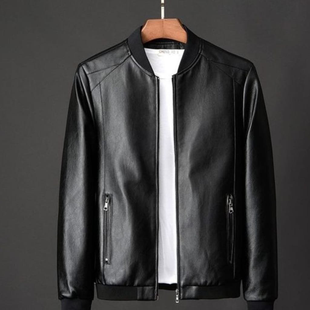 A classic black leather bomber jacket hanging on a wooden hanger against a dark background. The jacket features a ribbed collar, cuffs, and hem, with a front zipper and zippered pockets.