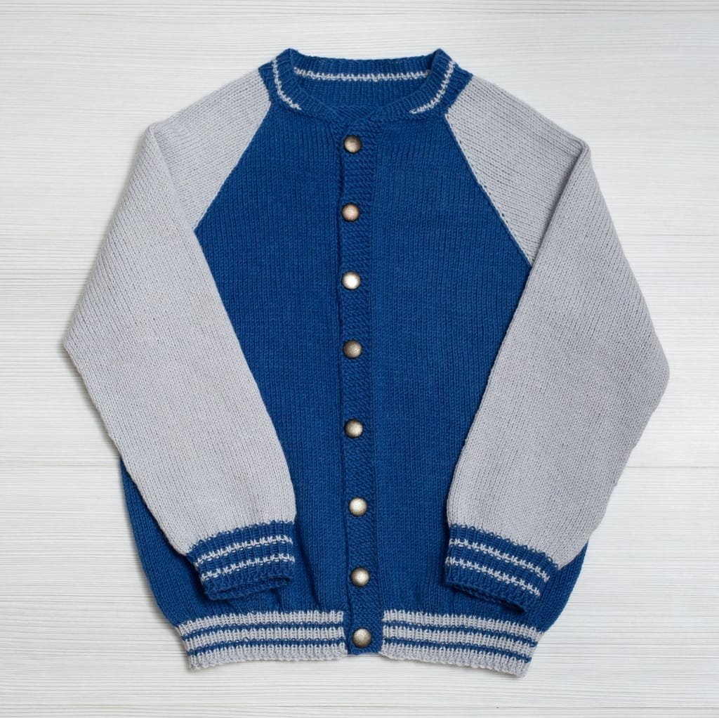 A stylish men's varsity wool jacket featuring a blue body with gray sleeves, snap buttons down the front, and striped ribbed cuffs and collar.