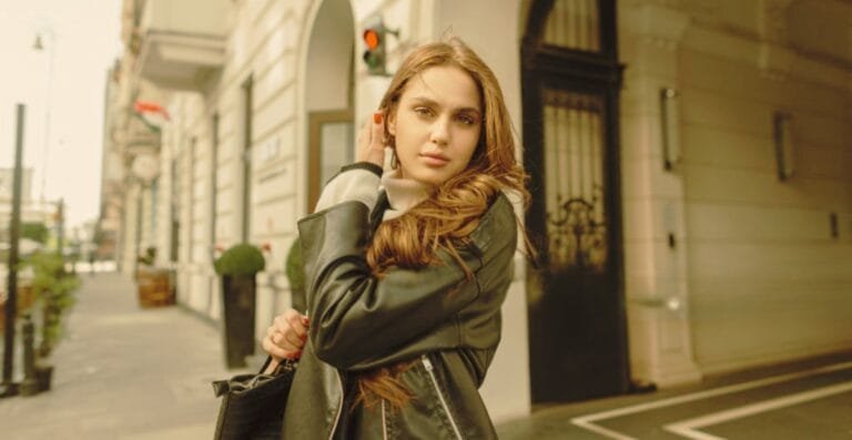 Young woman in a stylish black leather blazer posing confidently on a city street.