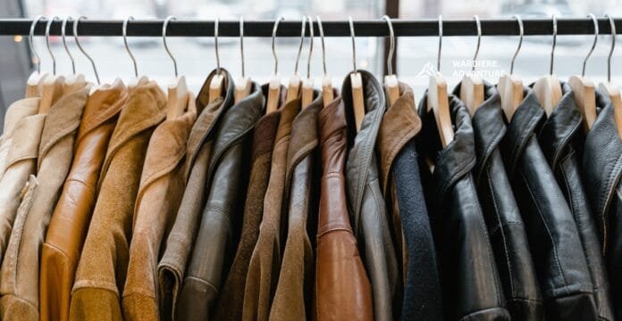 A row of jackets hanging on a clothing rack, featuring various shades of brown, black, and gray leather and fabric jackets.