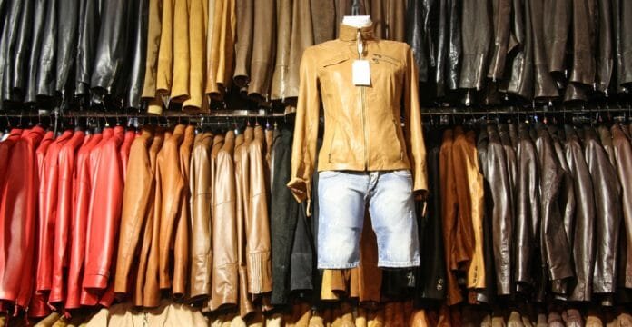 A display of leather shirt jackets hanging on a clothing rack, with a mannequin dressed in a tan leather shirt jacket and denim shorts in the center.