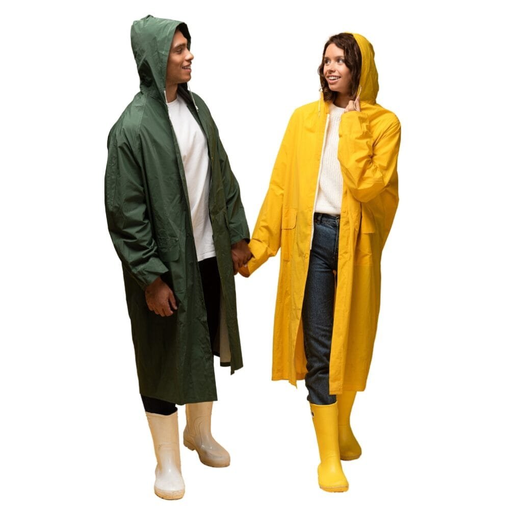A woman wearing a bright yellow long windbreaker jacket with a hood, smiling and holding hands with a man in a green windbreaker jacket, both dressed for rainy weather with yellow rubber boots.