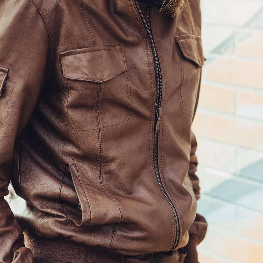 Close-up of a brown nubuck leather shirt jacket featuring front chest pockets, a zipper front, and a stand collar.