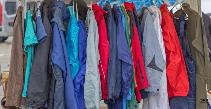 A row of colorful raincoats hanging on a clothing rack at an outdoor market.