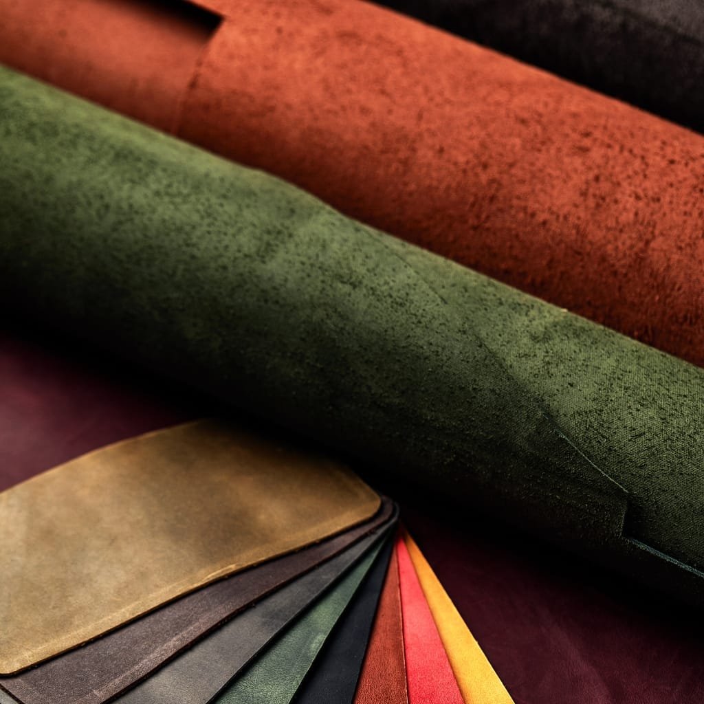 Close-up image of rolled and fanned sheets of leather in various colors, including green, red, black, yellow, and brown, showcasing the texture and thickness of Split Leather.


