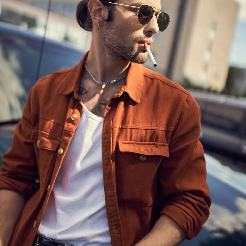 Man wearing a brown suede leather shirt jacket paired with jeans for a relaxed weekend look.