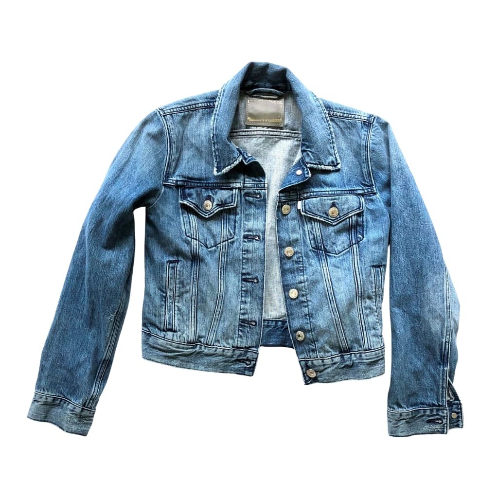 A classic blue denim jacket with button closures and chest pockets, laid flat on a plain white background