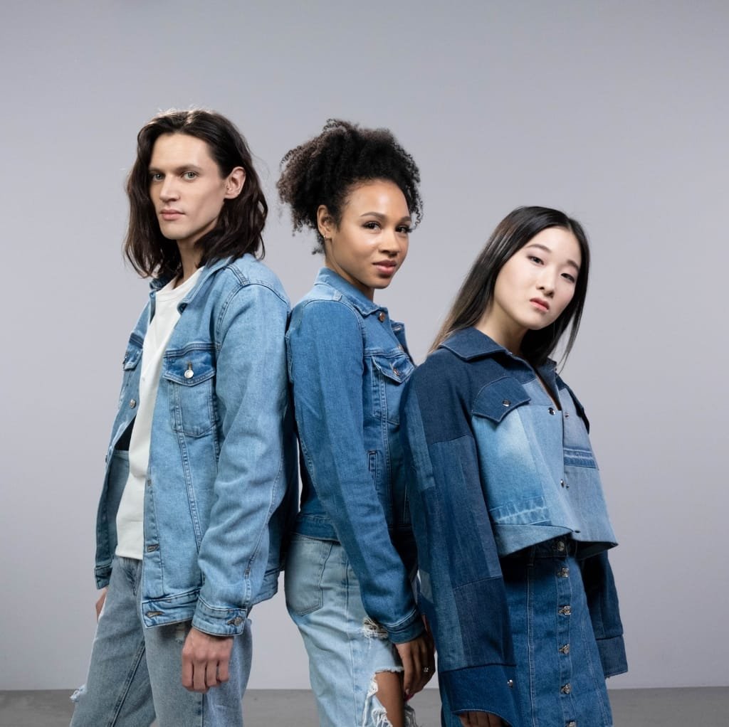 A young woman with dark hair, dressed in a denim jacket and black top, confidently posing outdoors, symbolizing self-expression and youthful style.