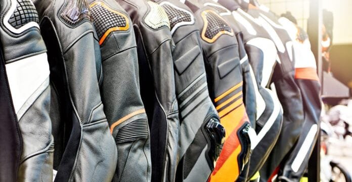 A lineup of men’s motorcycle racing jackets hanging on display, featuring various colors and designs with padded shoulders and protective elements.