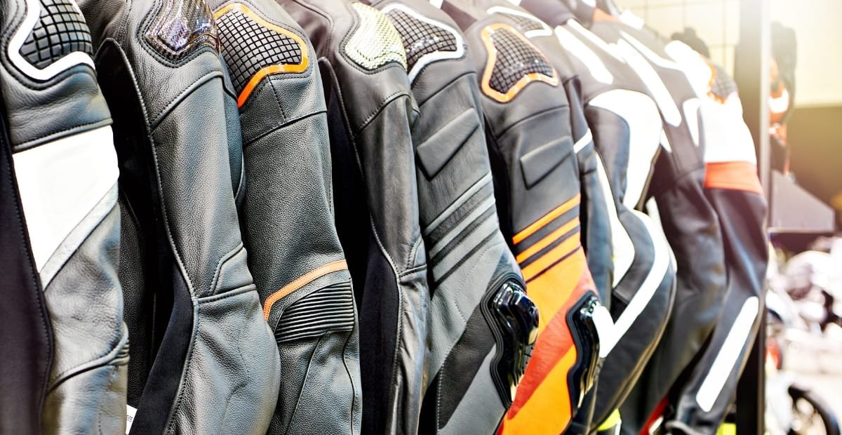 Top Racer Jacket Looks That Never Go Out of Style A lineup of men’s motorcycle racing jackets hanging on display, featuring various colors and designs with padded shoulders and protective elements.
