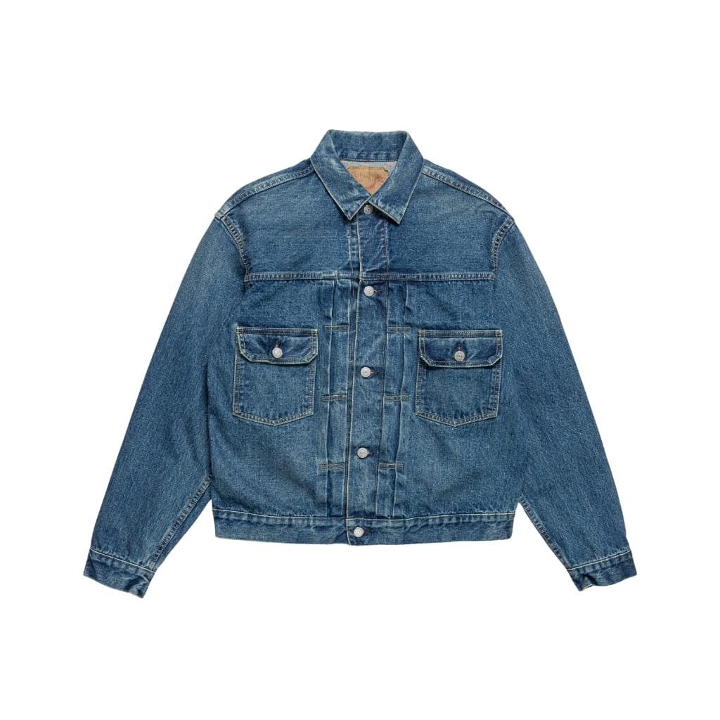 A classic blue denim jacket with long sleeves, a button-up front, and two chest pockets with flaps and buttons. The jacket features a traditional collar and visible stitching details.
