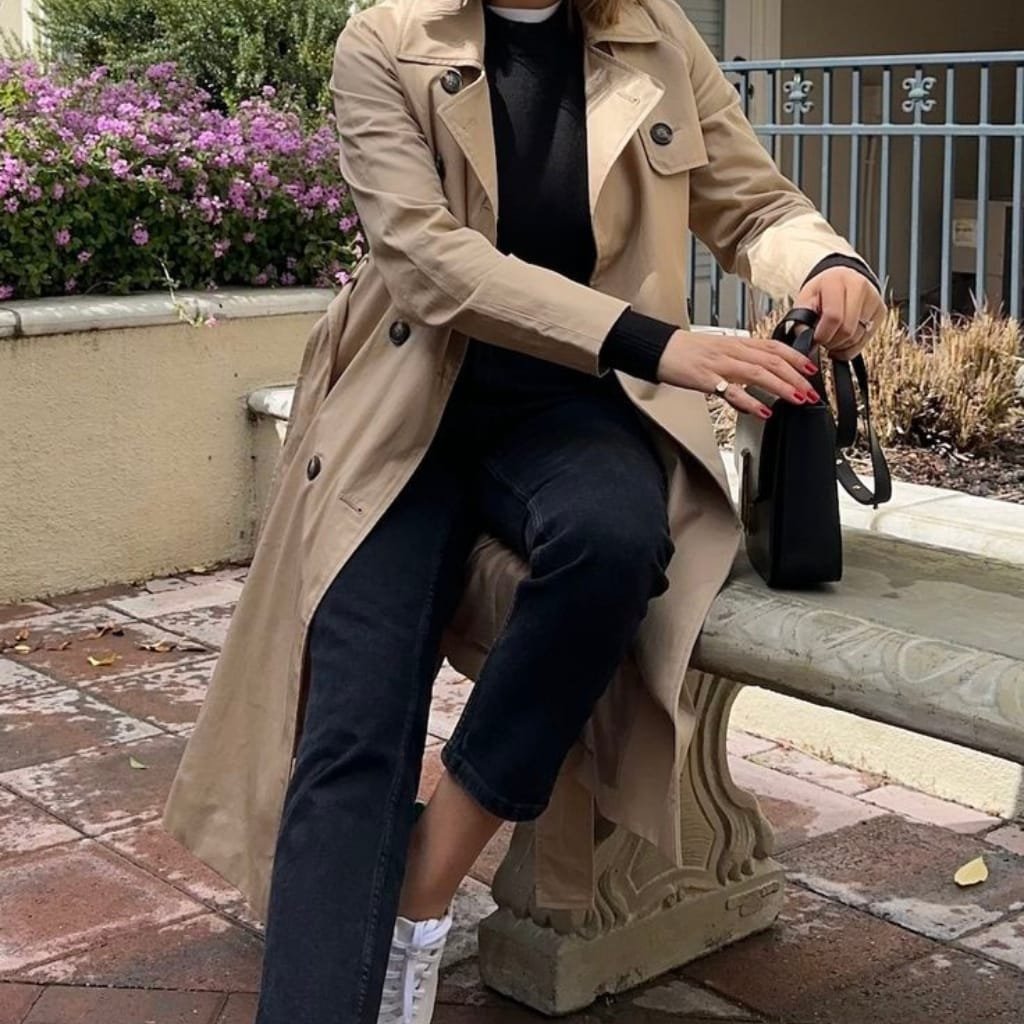 How to Style Trench Coats for Every Season 8 Woman wearing a relaxed trench coat with casual jeans and a striped top, styled for a weekend outing.