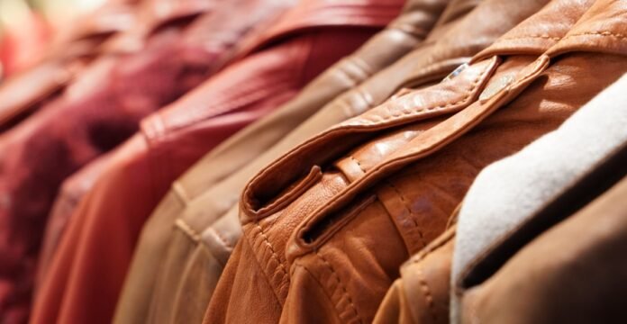 Close-up of several leather jackets hanging on a rack, showcasing various shades of brown and tan.
