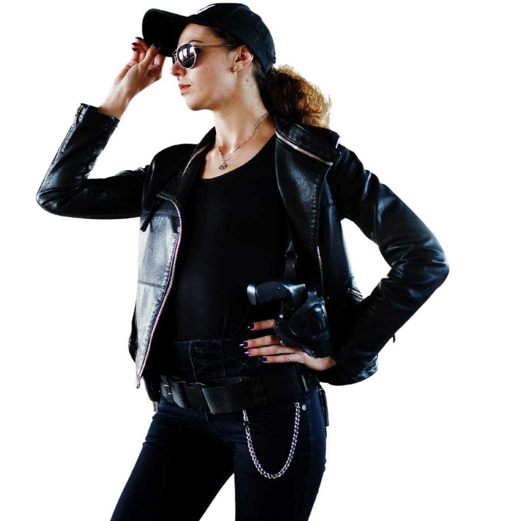 Top Racer Jacket Looks That Never Go Out of Style 10 A woman wearing a sleek, black leather racer jacket, paired with dark sunglasses, a black cap, and black pants with a chain accessory, striking a confident pose.