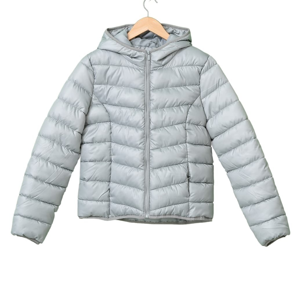 A light grey, quilted puffer jacket with a hood, front zipper, and horizontal stitching, hanging on a wooden hanger against a plain background.