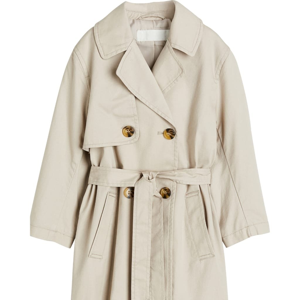 A classic beige ladies' trench coat with a double-breasted front, wide lapels, and a matching waist belt, featuring tortoiseshell buttons.