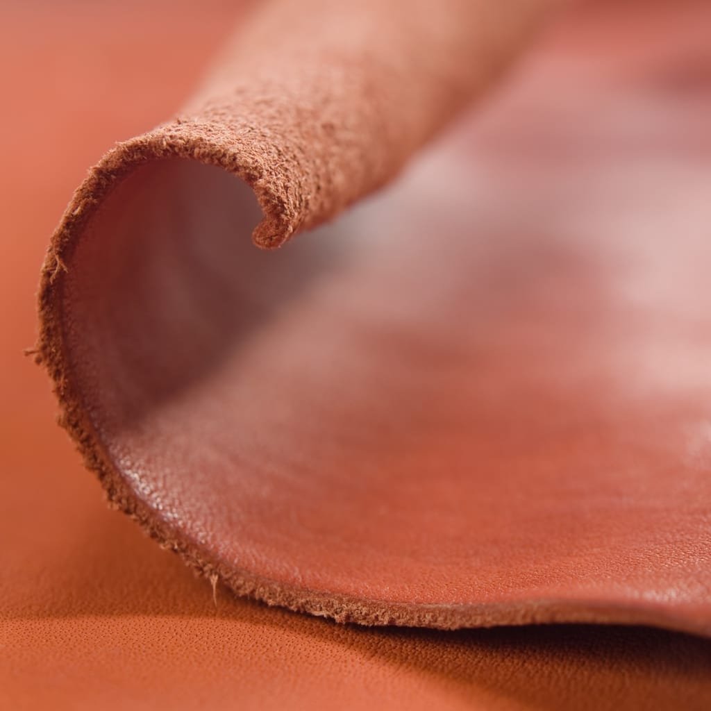 Close-up of a rolled piece of leather showing the textured surface with natural variations and a reddish-brown hue.

