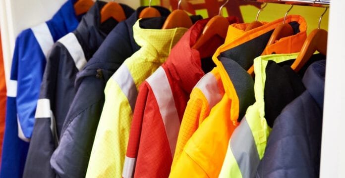 A row of colorful workwear lined jackets hanging on a rack, featuring various bright colors such as yellow, red, orange, and navy blue.