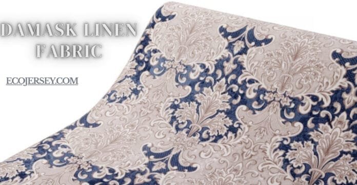 A close-up view of damask linen fabric featuring an intricate floral and scroll pattern in beige and navy tones.