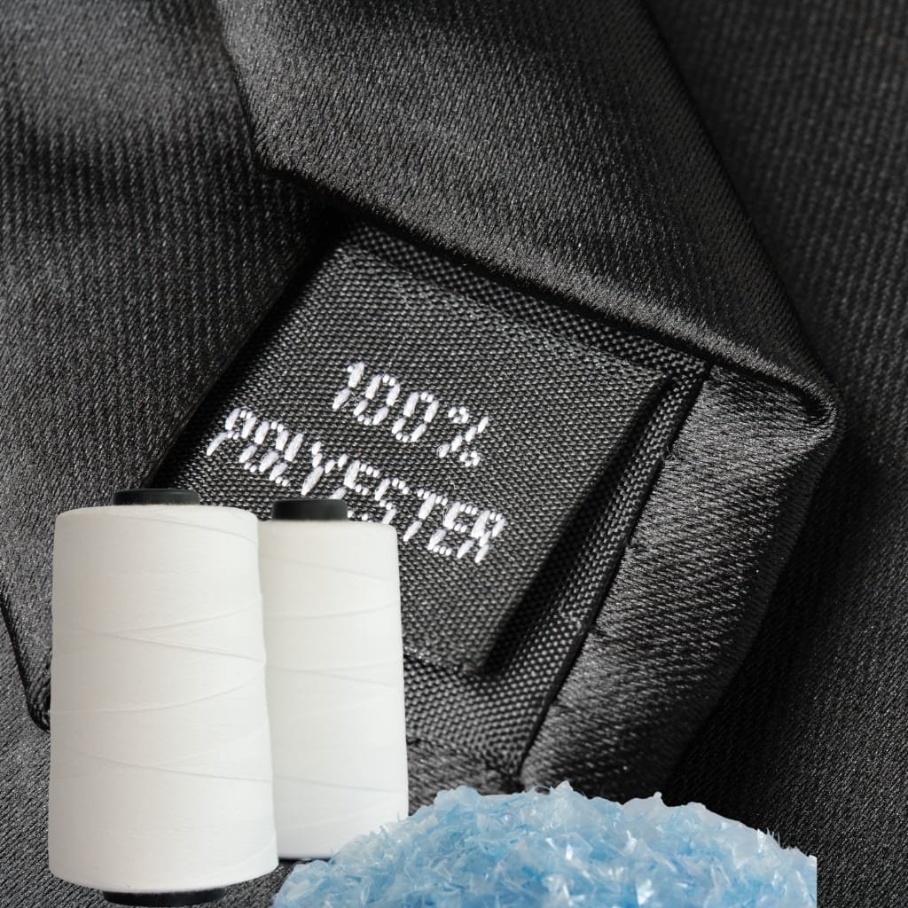 A close-up view of a black fabric label inside a garment showing “100% POLYESTER.” In the foreground are two white spools of thread and blue plastic pellets, symbolizing raw materials, with a dark textured fabric backdrop. "Process of Spinning Polyester"