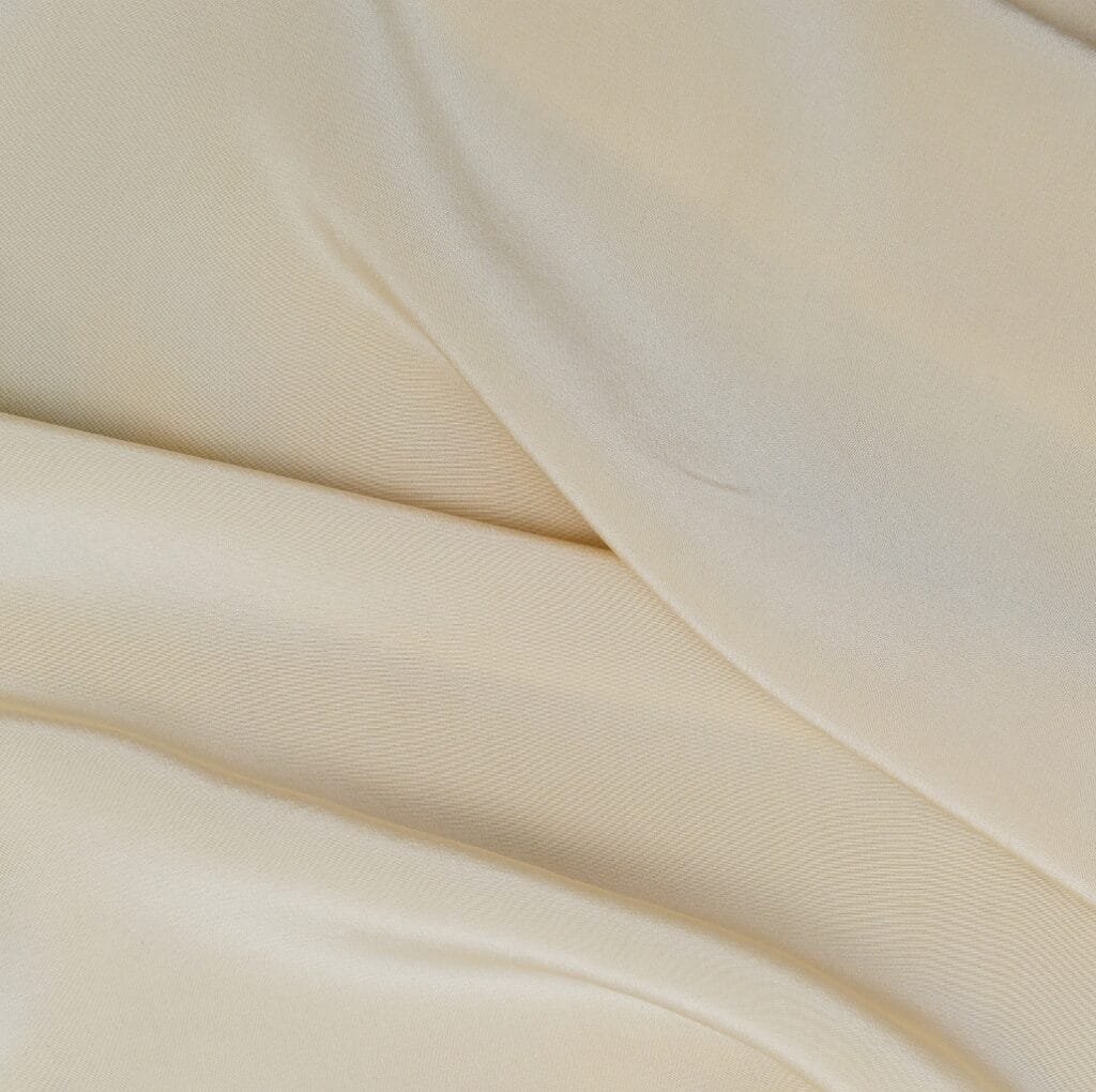 Close-up image of soft, cream-colored Holland linen fabric with gentle folds and a smooth, slightly textured surface.