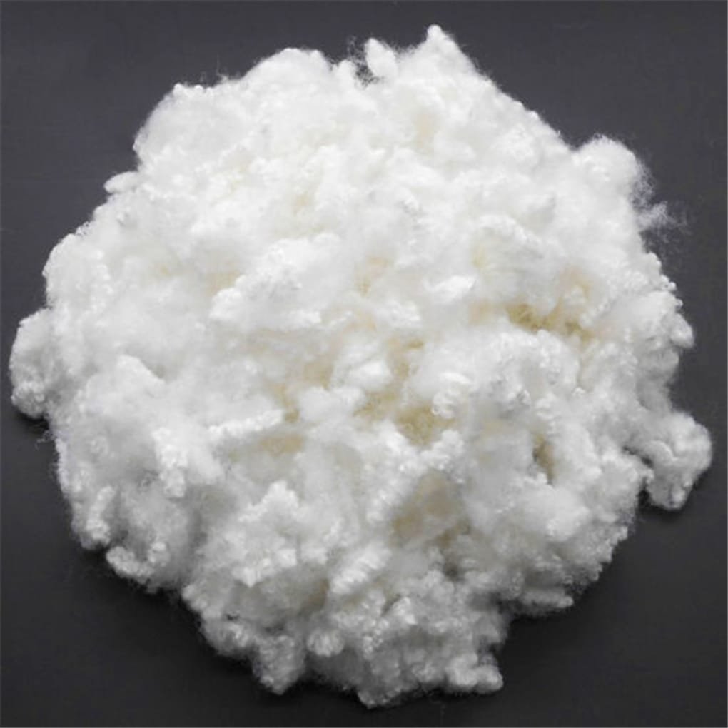 A fluffy, white crystalline powder piled into a chunky mound on a dark surface.