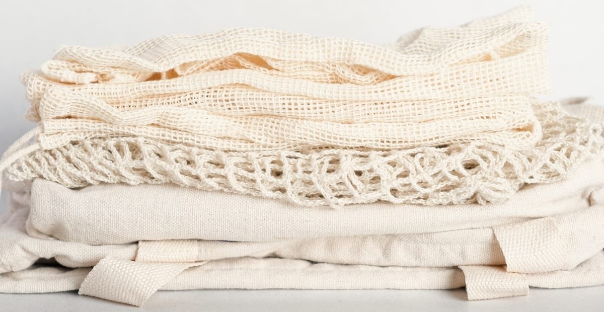 Loose Weave Linen: The Secret to Relaxed Chic Style A stack of light, natural-colored linen fabrics with varied textures, including a loose, open weave on top and tighter weaves beneath.