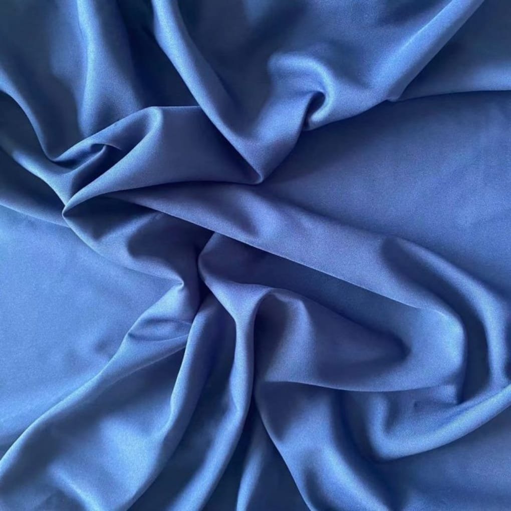 Smooth royal blue satin fabric draped and folded, showing soft sheen and fluid folds.