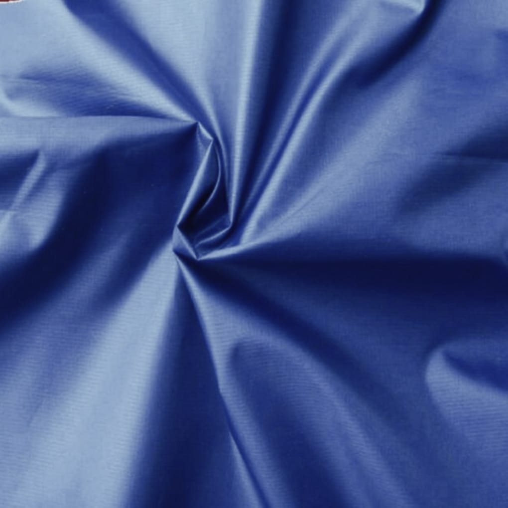 A close-up of blue satin-like fabric, showing glossy surface, soft folds, and a central twist creating a small gathered area.