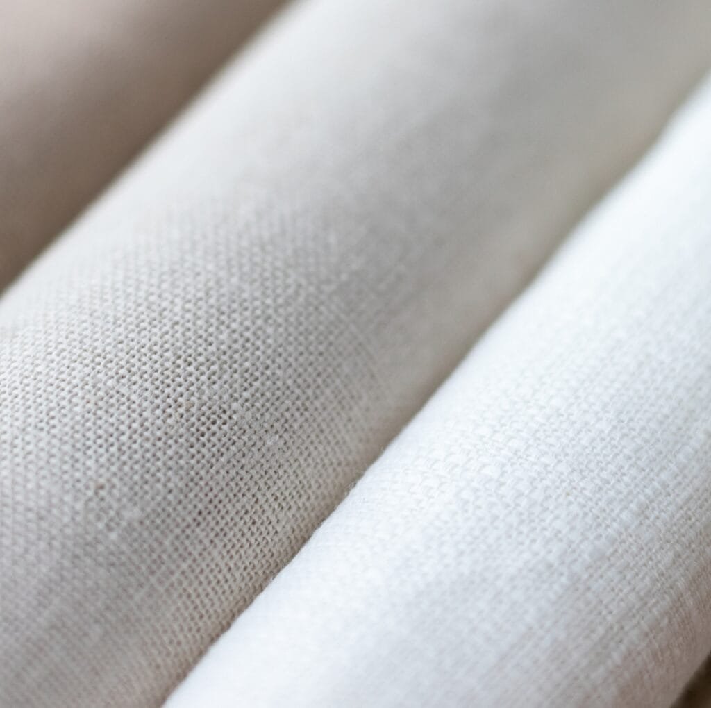 Close-up of light beige cambric linen fabric showing a tight, even weave and soft texture.