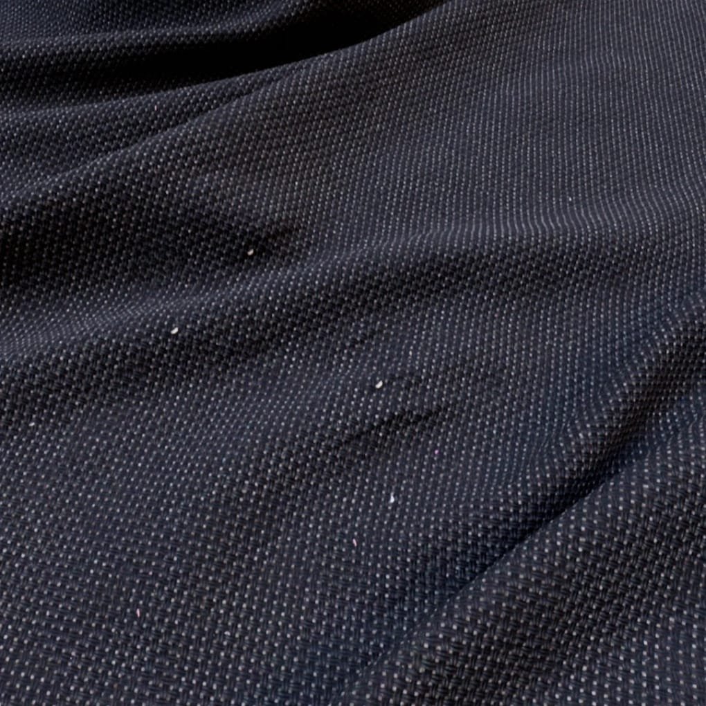 Close-up of dark navy fabric with a small woven texture and subtle folds, showing tiny specks.
