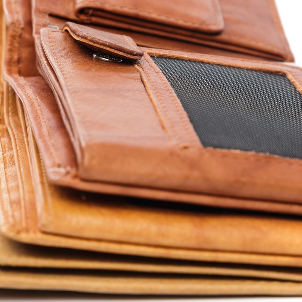 Close-up image of a brown leather bag, showing detailed textures, stitching, and a zippered compartment.